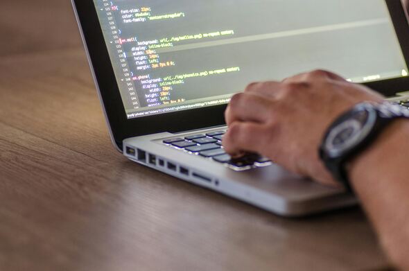 image of a computer with code on the screen and a person's hands typing on the keyboard